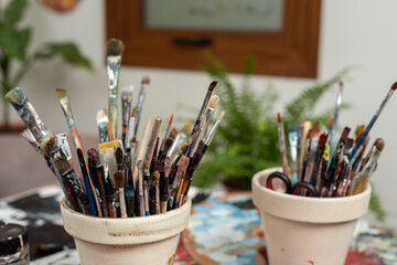 many brushes in a brush holder full of paint from a plastic artist with which he paints his works of art