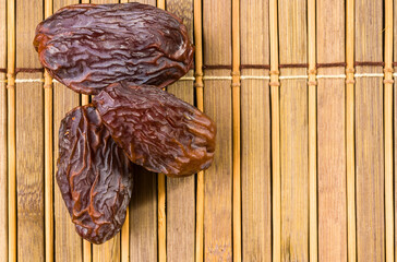 Big luxury dried date fruit on the bamboo mat, kurma ramadan kareem concept, close up.