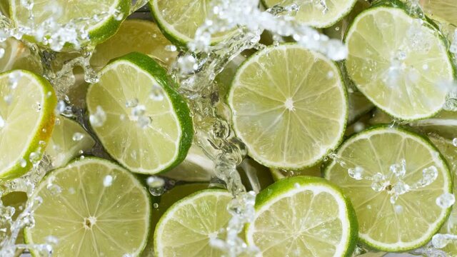 Super slow motion of lime slices with splashing water, top view. Filmed on high speed cinema camera, 1000 fps.