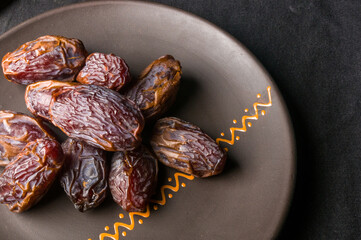 Big luxury dried date fruit in bowls on the dark surface, kurma ramadan kareem concept, close up.