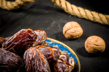 Big luxury dried date fruit in bowls on the dark surface, kurma ramadan kareem concept, close up.