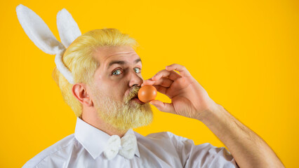 Man with rabbit ears kiss Easter egg. Eggs hunt. Bunny man. Spring holidays.