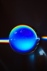 Rainbow beam being bent through the refraction of a glass marble, displaying just a part of the...