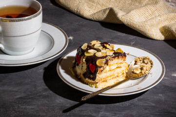 Still life - layered homemade sponge cake and a cup of black tea in a white dish, and a linen...