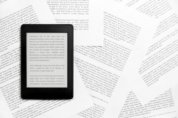 Fototapeta premium Electronic reader with the screen on and a text on it, on paper sheets.