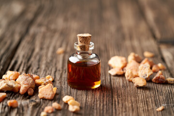 A bottle of styrax benzoin essential oil with benzoin resin on a table