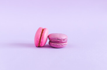 Tasty french macarons on a violet pastel background. Pink and violet macarons.