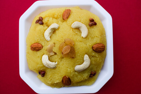 Traditional Indian dessert sweets made of semolina or rawa known as Kesari bath decorated with nuts garnished. south asian sweet on red background. blank space to write fonts text for greetings