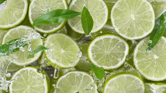 Super slow motion of lime slices with splashing water, top view. Filmed on high speed cinema camera, 1000 fps.