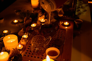 Tea ceremony, candles roses and stones, spa relaxation. Pours boiling water into a teapot. Muffled light