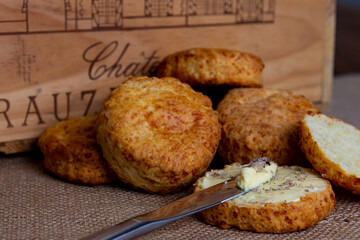 Landscape orientated photograph featuring a buttered cheese scone with silver knife topped with sea salt.