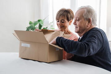 Happy senior couple unpacking parcel box from online delivery service - Focus on woman face