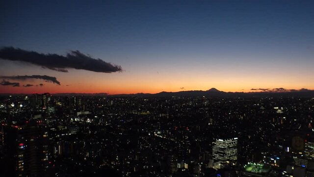 TOKYO, JAPAN : Aerial view of sunrise CITYSCAPE and MOUNT FUJI. Rising sun, beautiful dawn sky and buildings. Japanese city life and nature concept. Long time lapse zoom in video, night to morning.
