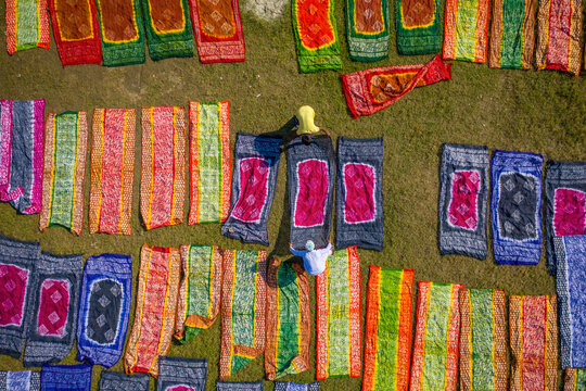 Aerial view of people working in a public laundry draining and drying colourful clothes at sunlight, Araihazar, Dhaka province, Bangladesh.