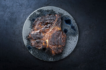 Modern style traditional barbecue dry aged wagyu porterhouse beef steak bistecca alla Fiorentina served as top view on a Nordic design black plate with copy space