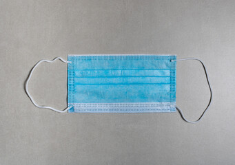 mask for personal use in combating the pandemic of the covid-19 light blue with white elastic on a gray background.