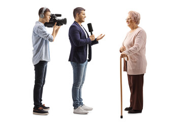 Full length profile shot of a male reporter with a microphone and a cameraman interviewing an...