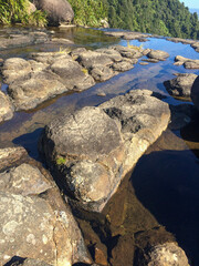 step on stable flat huge rocks in clear, quiet low tide river on top of a mountain during summer when the falls is almost dry