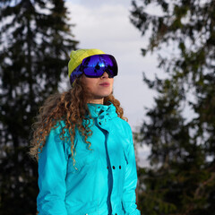 Close up portrait of a bright snowboarder girl in a blue sun-protection mask.Winter rest in the...