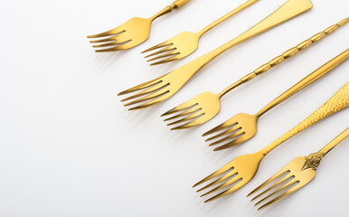 Many golden forks on a white background, golden cutlery