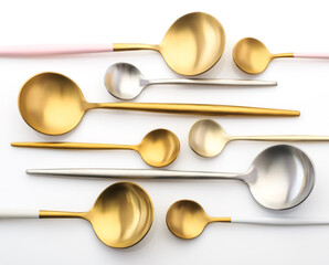 Many different metal spoons on a white background. Gold and silver spoons, teaspoons