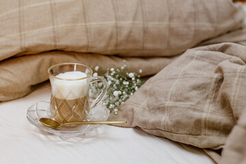 Fototapeta na wymiar Cappuccino coffee on bed, cozy still life, morning concept, blogger style, warm styled still life