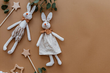 Two rabbits with wooden toys  on brown background. Top view, flat lay