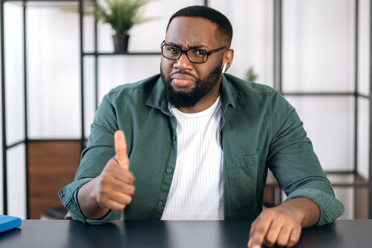 Portrait Of A Friendly Successful Bearded African American Guy With Eyeglasses, Sitting At A Table And Showing A Thumbs Up Gesture, Looking Directly Into The Camera