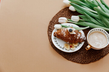 Flat Lay, coffee, croissant and white tulips. Breakfast on Mothers day, Valentines Day or Women day. Romantic morning concept surprise