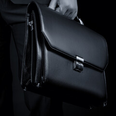 Black leather briefcase on a black background. Business style.