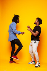 two african american guys posing cheerful together on yellow background, lifestyle people concept