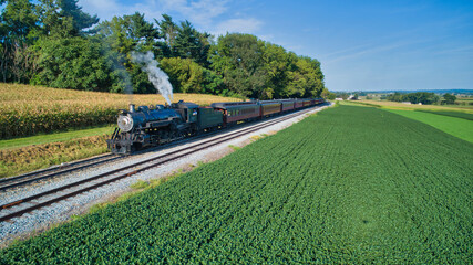 Aerial View of An Antique Restored Steam Locomotive Blowing Smoke and Steam Traveling Thru Farmlands and Countryside on a Sunny Summer Day