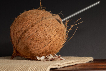 A whole and sliced coconuts on jute.