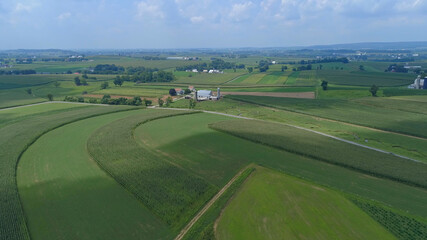 Fototapeta na wymiar Aerial View of Green Farmlands With Different Crops Growing in the Fields on a Sunny Day