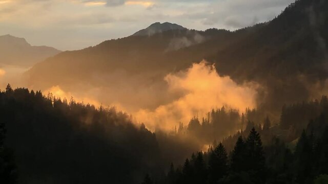 rosa Nebel bei Sonnenuntergang in den Bergen der Alpen in &Ouml;sterreich. Fantastisches Spiel der Sonnenstrahlen Berge in magischem Nebel mystische Landschaft unter dem Nebel der Nebel erzeugt Illusion