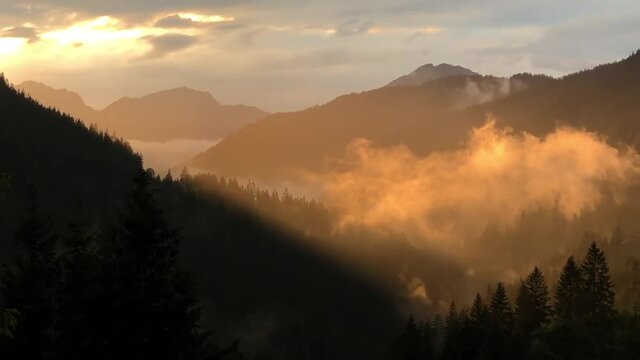 rosa Nebel bei Sonnenuntergang in den Bergen der Alpen in &Ouml;sterreich. Fantastisches Spiel der Sonnenstrahlen Berge in magischem Nebel mystische Landschaft unter dem Nebel der Nebel erzeugt Illusion