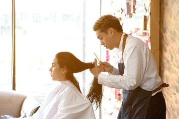 Asian male hairdresser make hairstyles for Asian female customers in modern beauty salons in Bangkok city.