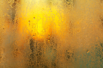 Ice on the window glass in warm light . Mate and cold surface