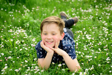 Spring boy on grass. Cute kid on field flower. Dreaming child.