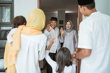 Obraz premium Happy asian muslim aged couple meeting kids and grand children at doorstep during eid mubarak celebration