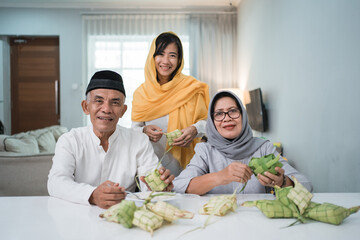 senior muslim couple and daughter making ketupat for eid fitr mubarak celebration at home