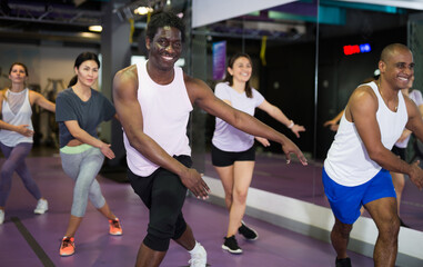 Group of active people practicing together in gym