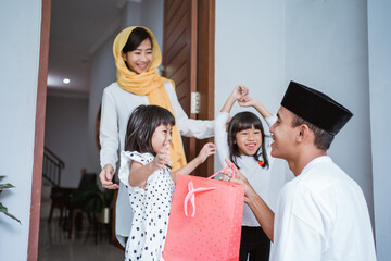 portrait of muslim father giving a gift to his children on eid mubarak