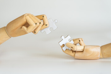 Business Solution Concept. Closeup of wooden hand model holding puzzle jigsaw on white background.