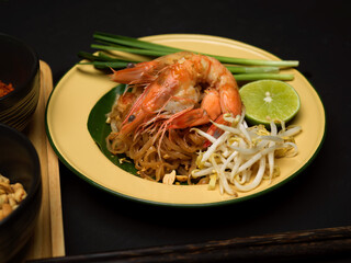 Stir fired Thai noodles with shrimps serving on traditional plate with lime, beansprouts and chives, Pad Thai