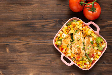Baked chicken with vegetables on a wooden background. Top view. Copy space.