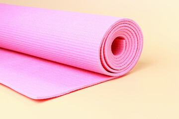 The pink sports mat for training on brown background close-up