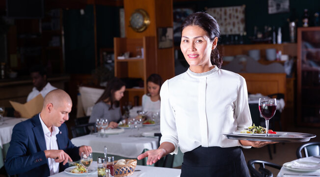 portrait of happy female garson standing in cafe