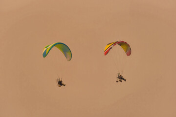 Silhouette of the Paramotor gliding and flying In the air through soft sunlight sky
