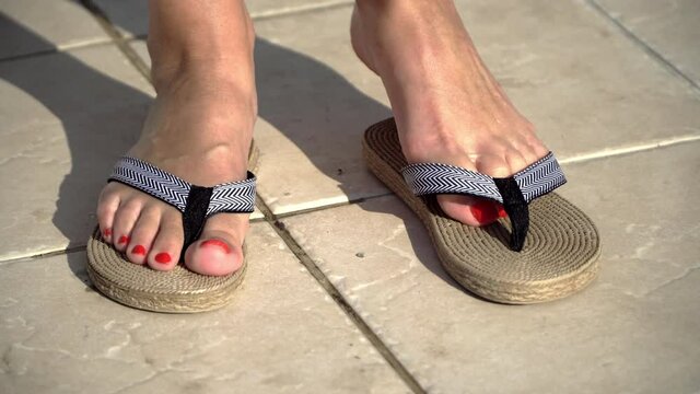 Female feet wear flip flops by the pool